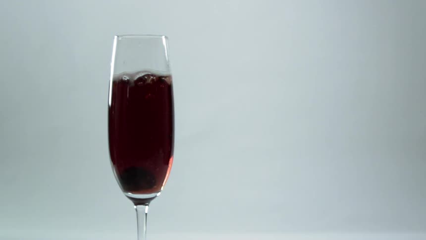 A chocolate covered garnish is dropped into a glass flute and sinks to the bottom