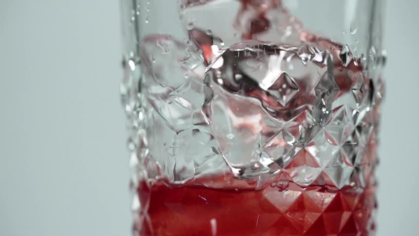 Red liquid is being poured into a glass