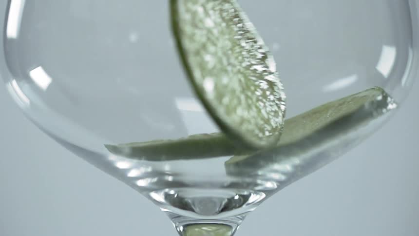 Three lime slices tumble into a drink glass