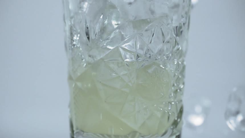 Ice being poured into a glass with liquid
