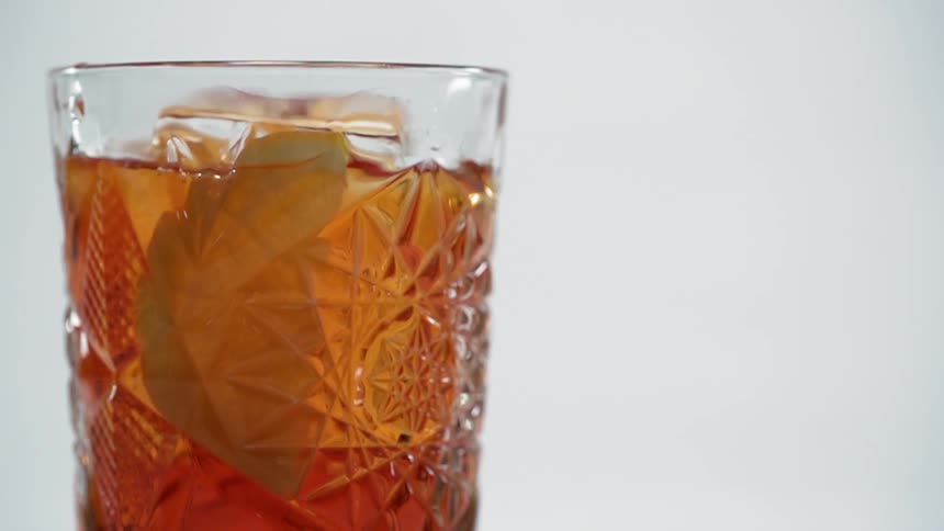 A lemon slice falling into a glass of old fashioned