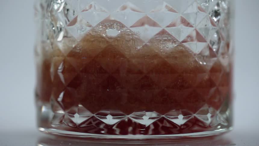 Dark colored liquid pours into a glass