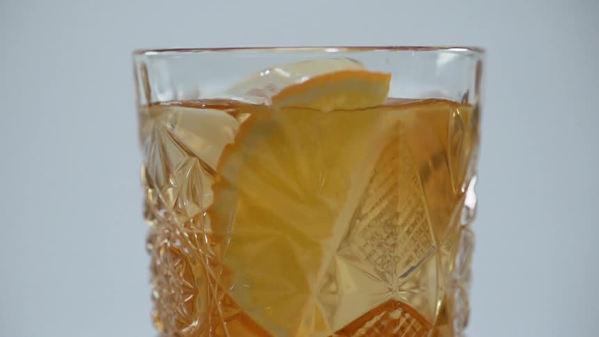 Orange slice falls into a glass of cocktail