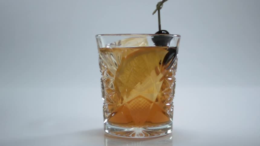 An olive is dropped into the drink