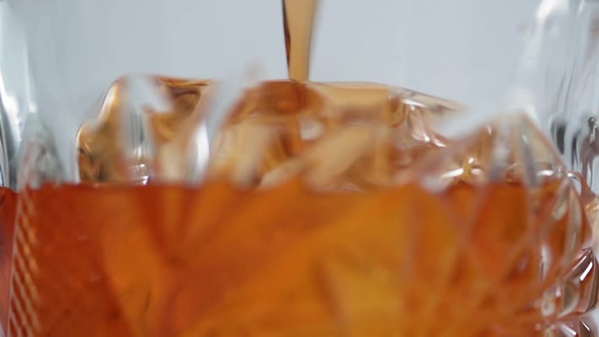 A cocktail being poured in to a glass