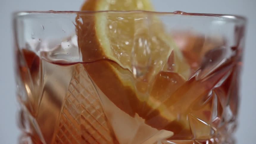 The orange wedge falls into the drink
