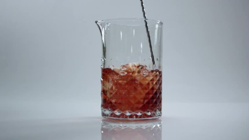 Alcoholic drink being stirred in clear glass pitcher