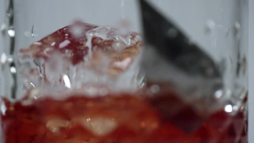 Ice cube being stirred in a glass jar with a metal stirrer