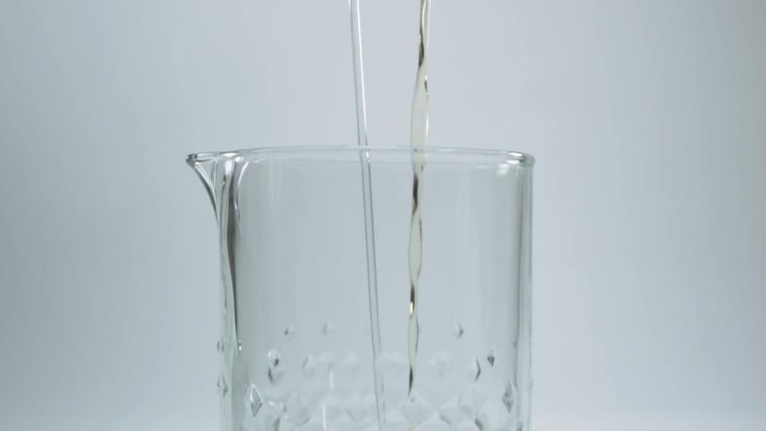 Two liquids are being poured at the same time in the same glass
