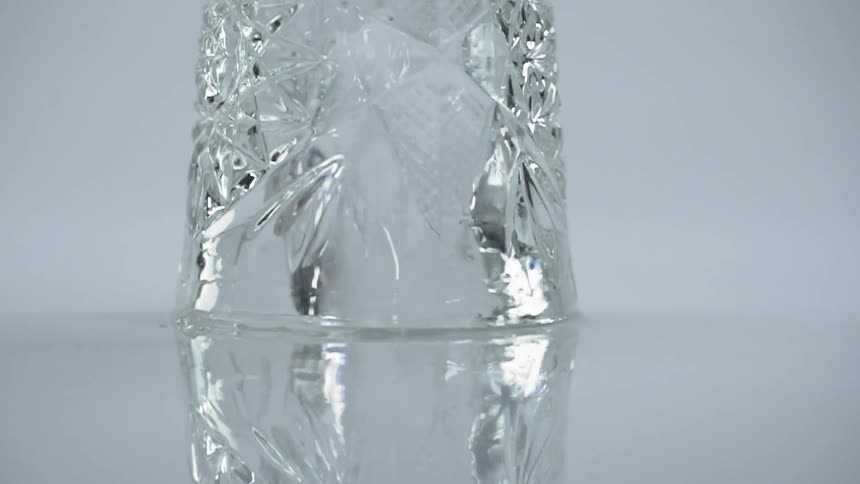 Faceted glass shines with inner object spinning inside and spreading water