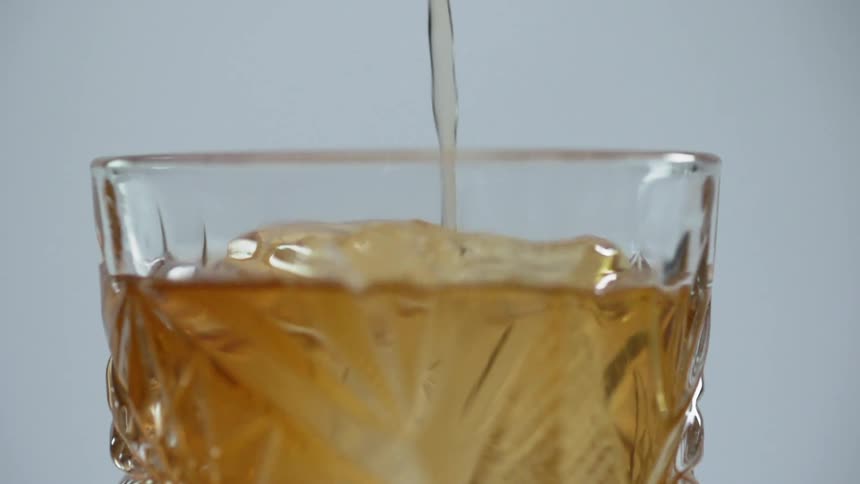 A drink being poured in to a cocktail glass