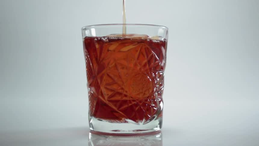 A drink being poured in a glass in a studio