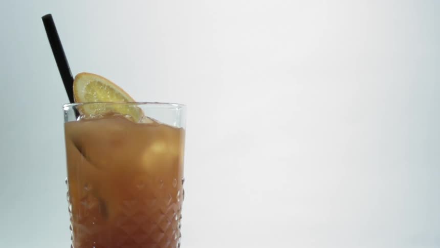 An orange slice drops into an alcoholic drink