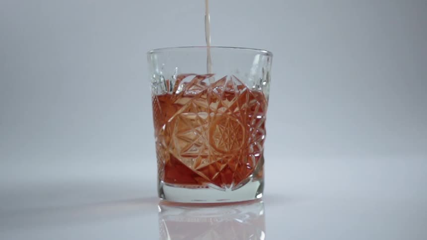 The drink is slowly being poured into the glass