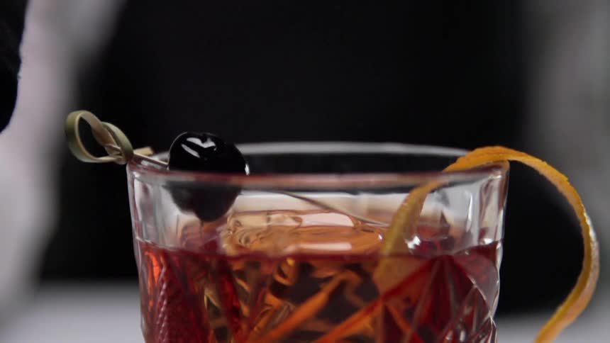 A bartender placing garnish atop a cocktail