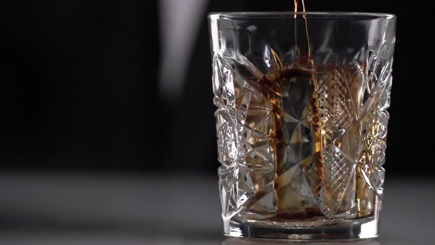 A person pours a beverage in to a glass