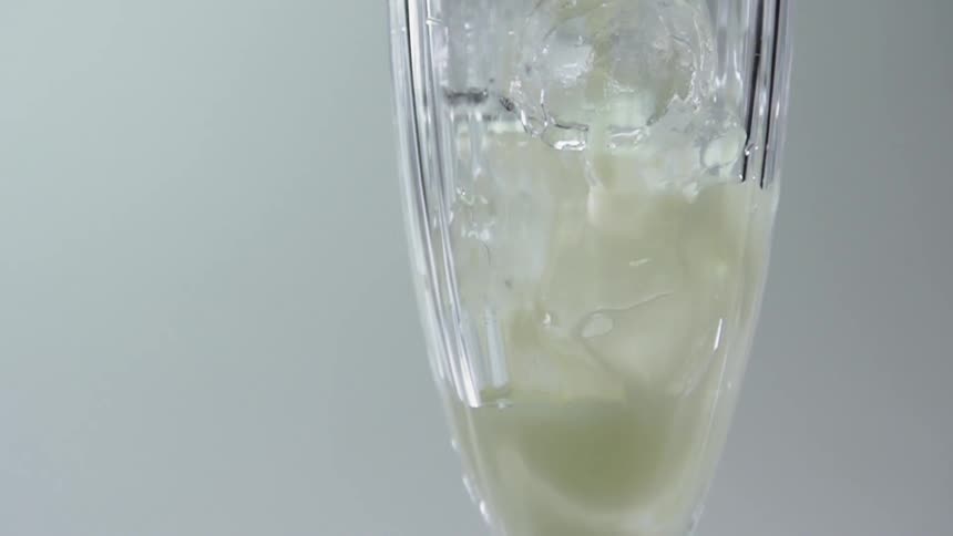 A cream colored liquid being poured into a glass with ice