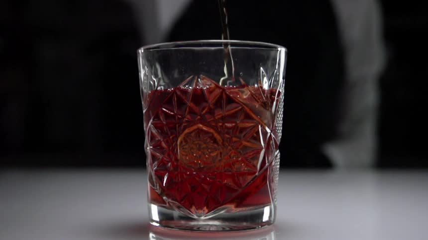 Reddish liquid is poured into clear faceted glass