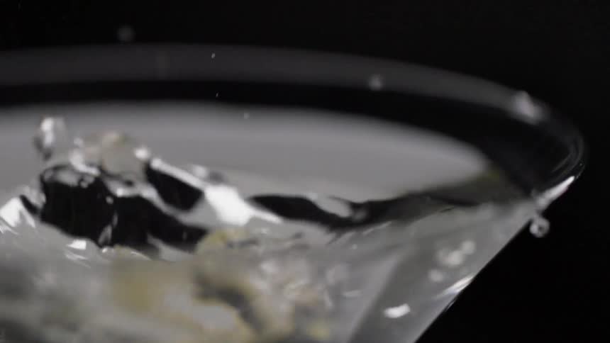 A lemon is being put into a alcoholic beverage