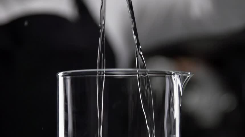 A person pours liquid in to a glass