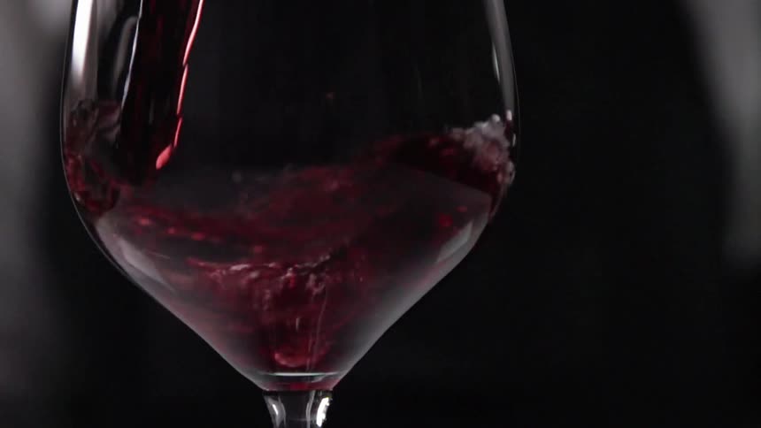 Close up of red wine being poured in a wine glass in slow motion