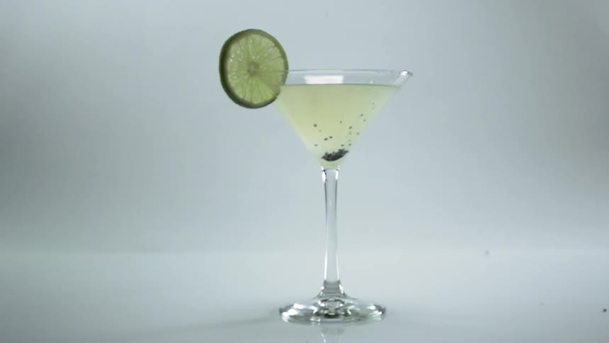 Herbs being dropped in a martini in a studio