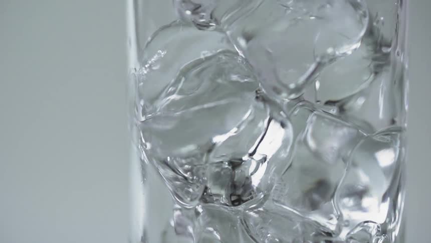 The glass full of ice is being filled