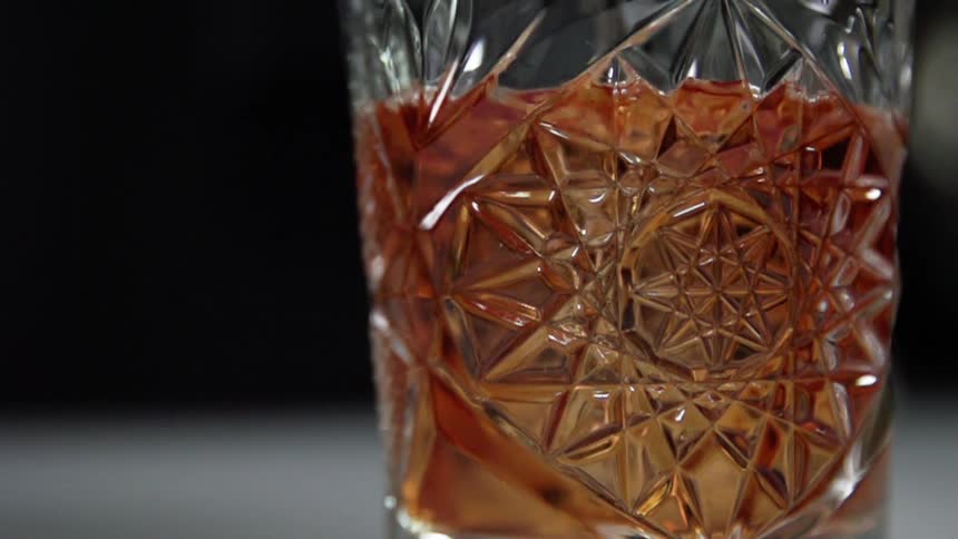Red cocktail is being poured into a glass