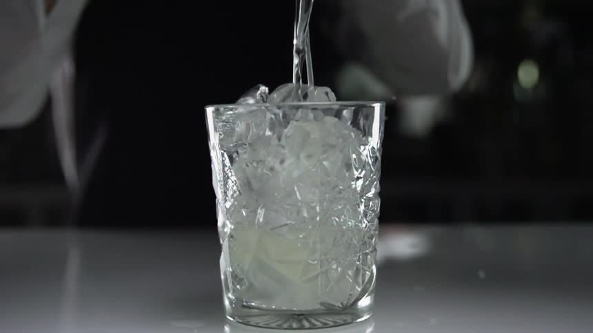 A barbender pours a drink in the glass