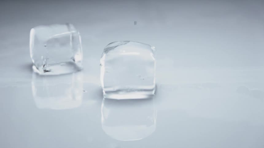 Two ice cubes sliding across hitting and chipping a corner off of one cube