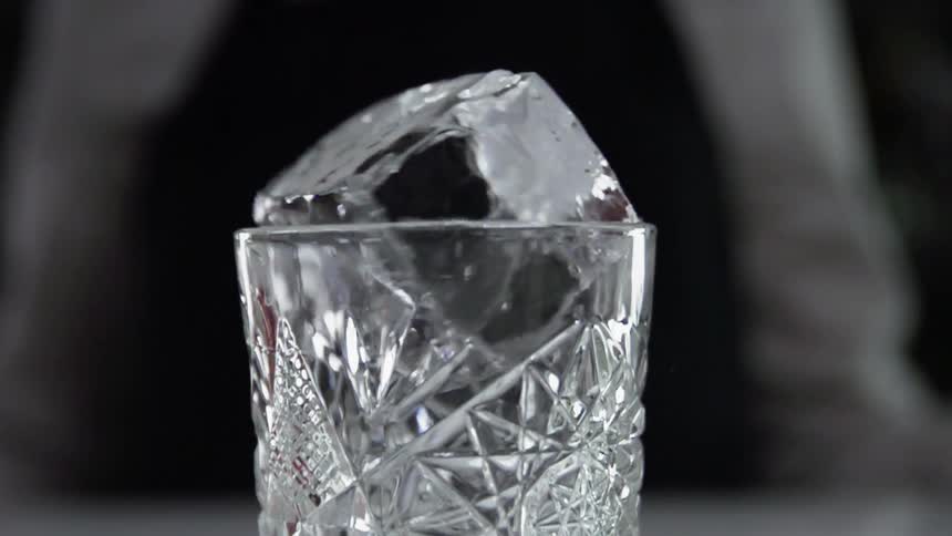 A person is putting an ice cube in a glass