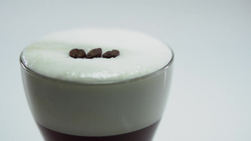 Coffee beans falling on top of a drink