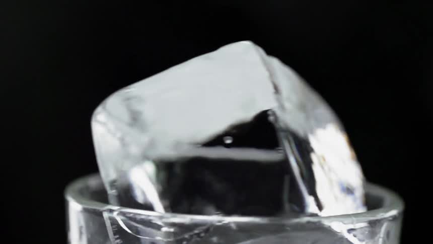 A glass with a large ice cube stuck in it spins around