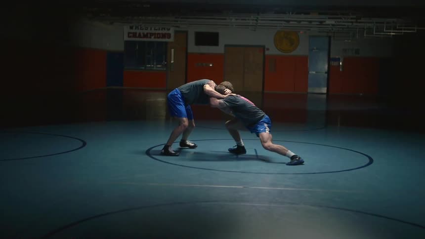 Two men are wrestling in a dark gym