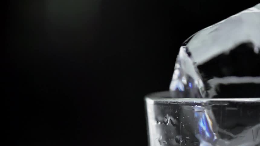 The ice cube spins on top of the glass
