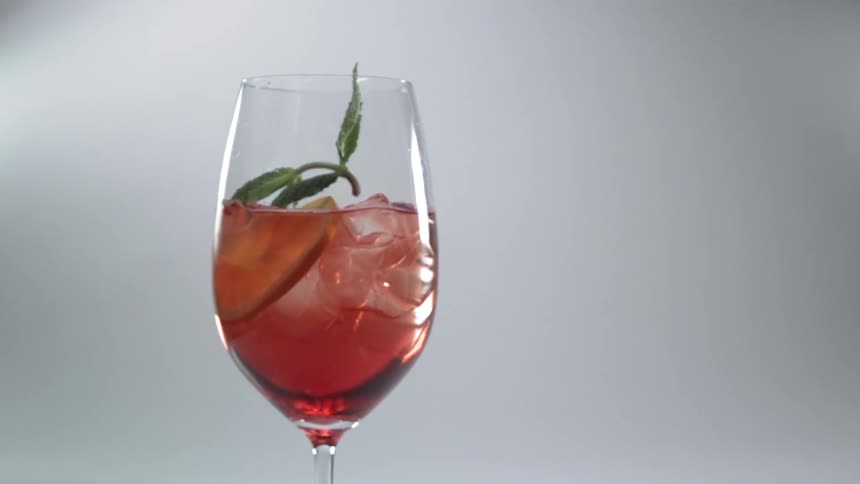 Sprig falling into a cocktail drink in a champagne glass in slow motion