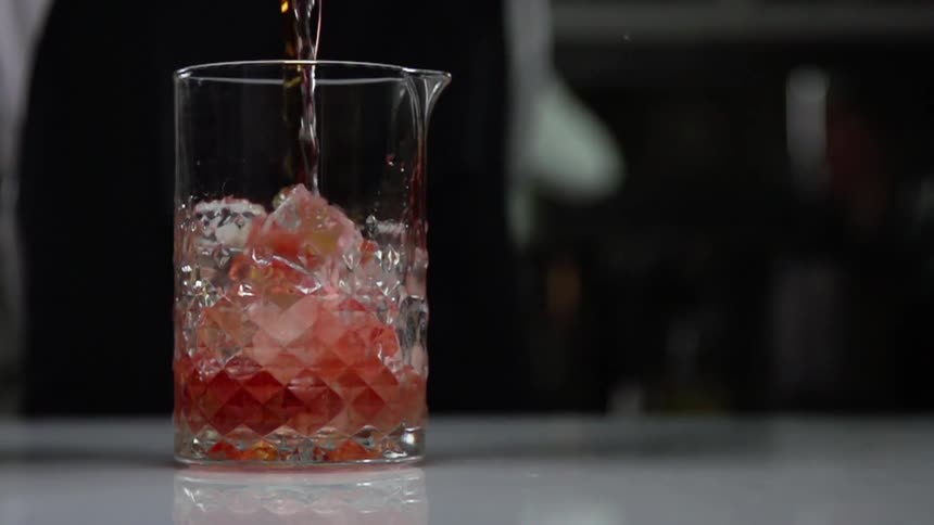 Reddish amber and clear liquids are poured into a faceted pitcher with a pour spout