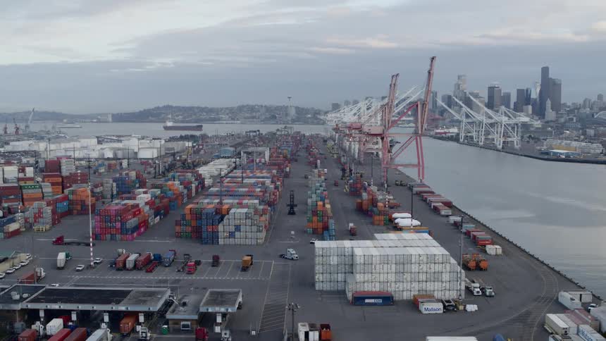 Containers and cargo are being stacked at a busy urban port facility