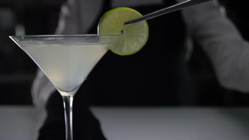 Lime being placed on rim of a martini drink at a bar