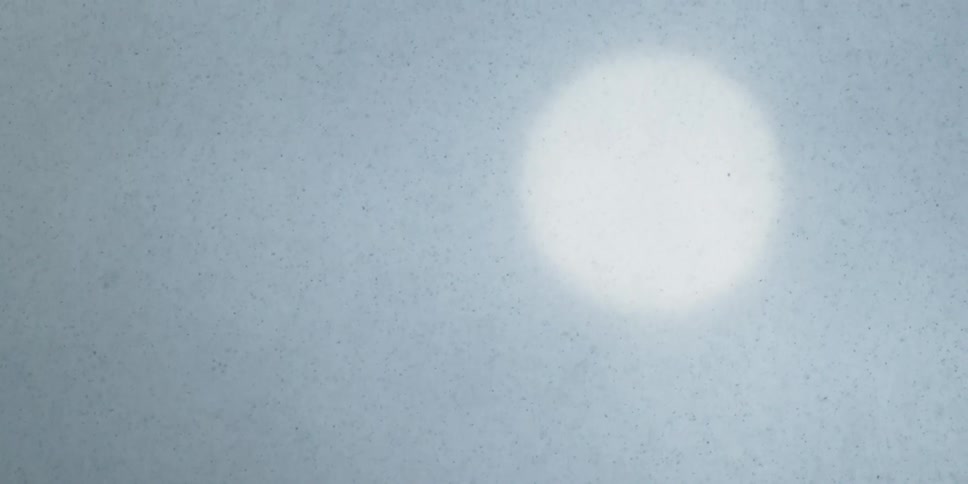 Snow falls in front of the sun