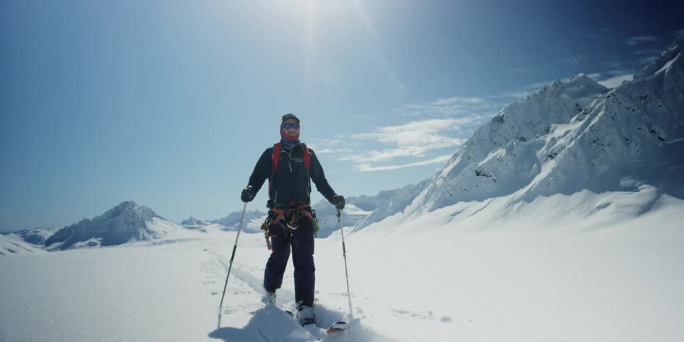 A man in cold weather gear crosses a frozen landscape on skis