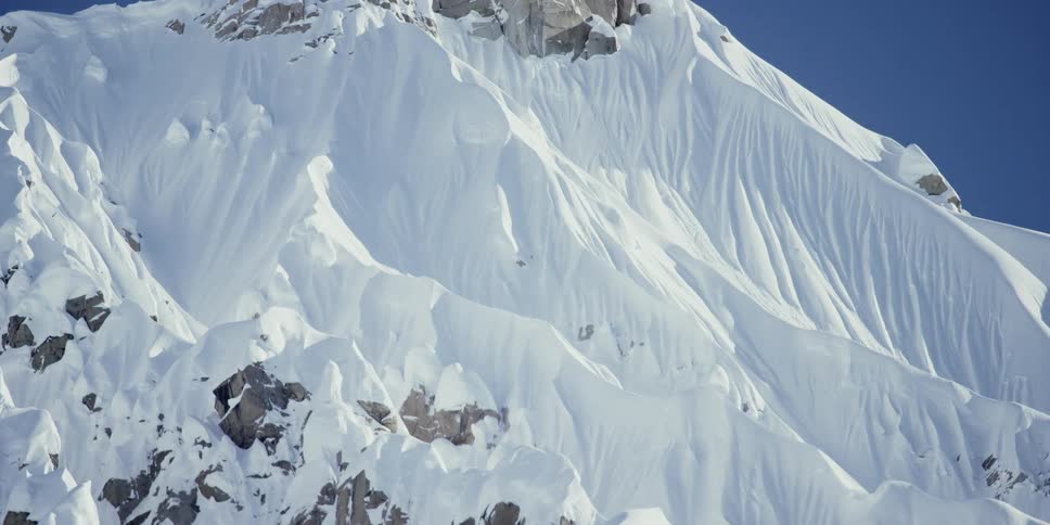 Snow covers the sides of a large mountain