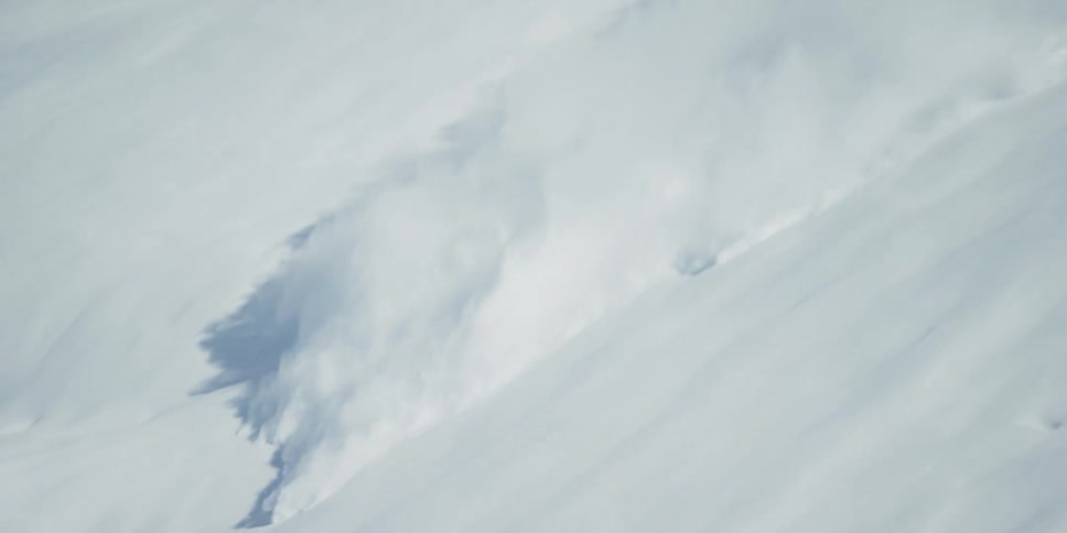An avalanche of snow races down the side of a mountain