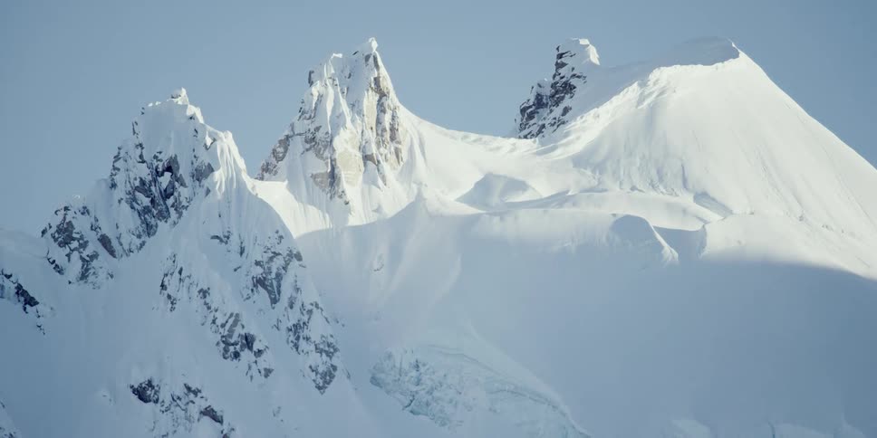 Shadows creep up the side of a snow covered mountain range timelapse