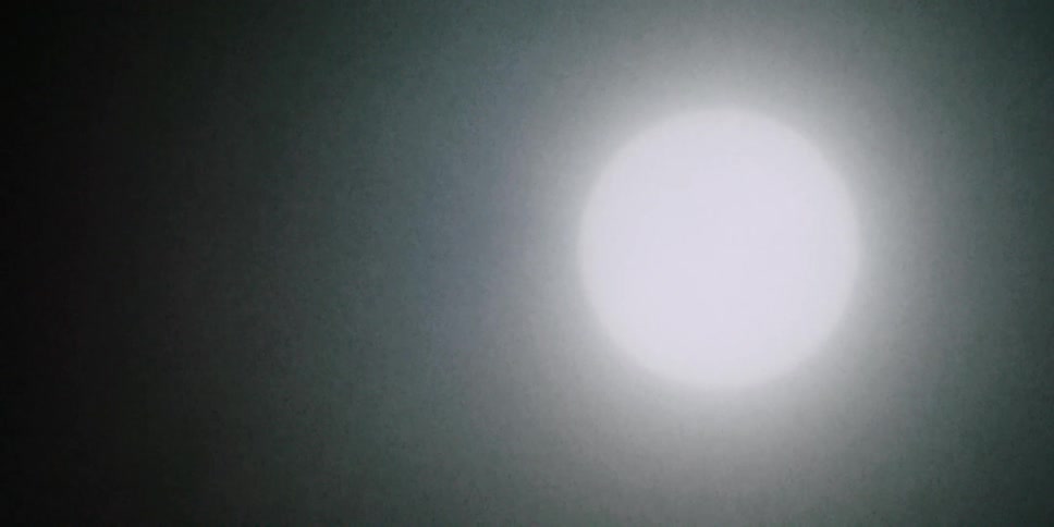 Light snow falls around the orb of the sun