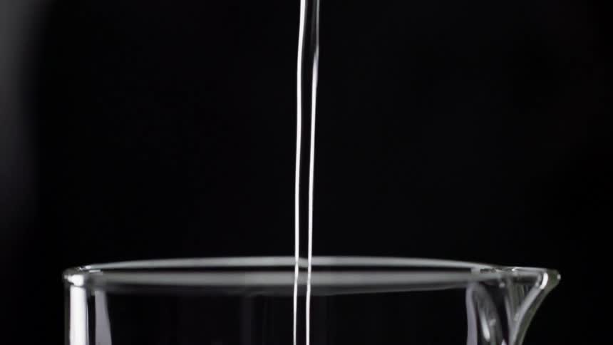 Water pours into a glass pitcher while another stream hits the rim and splashes on the side