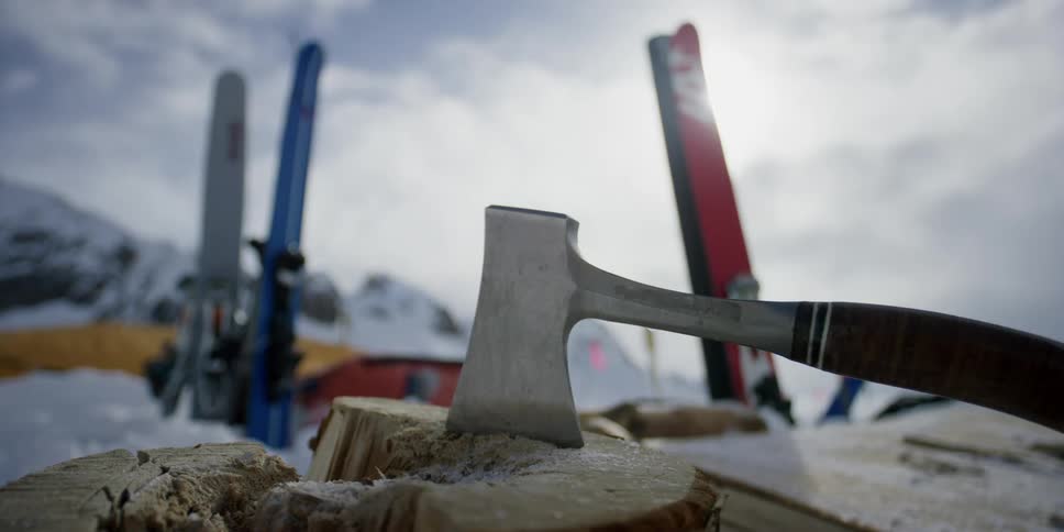 An ax and skis sit at a camping spot