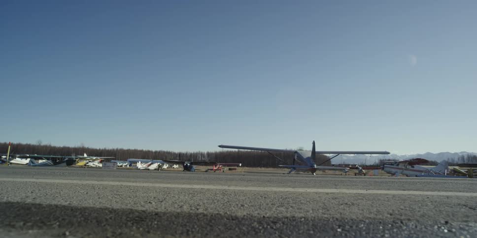 A plane moves down a runway as other planes sit parked off to the side
