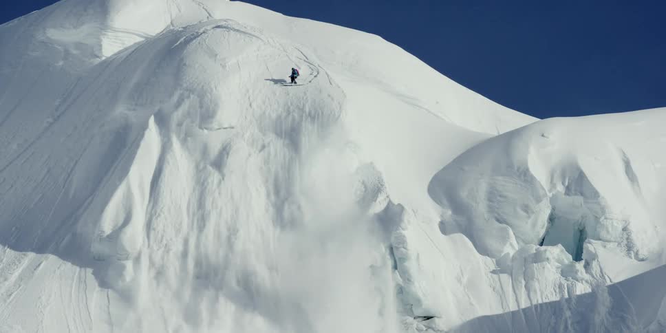 A skier sets off a small avalanche on steep slope