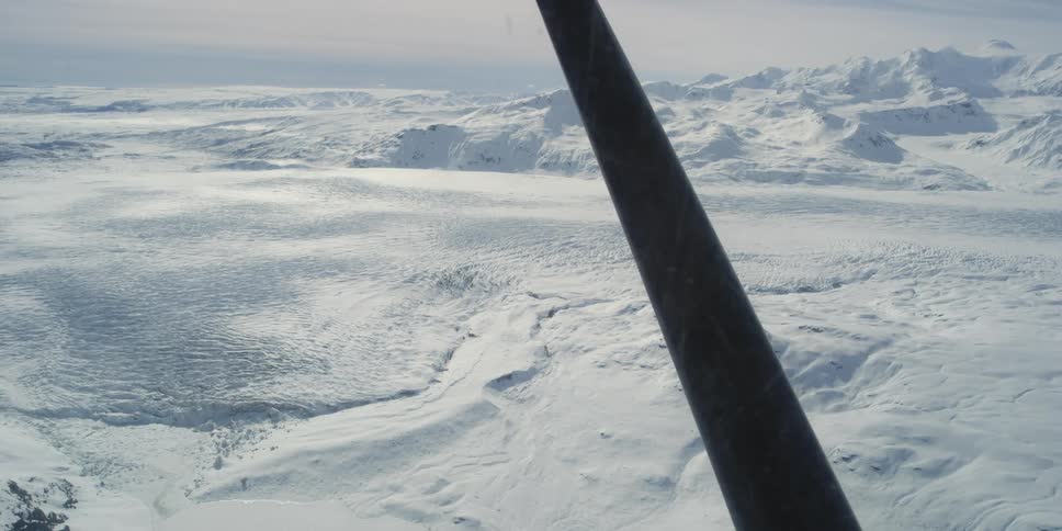 An airplane flies over an arctic region with glaciers